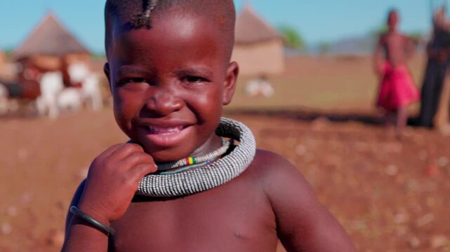 Smiling Himba child walking in traditional Namibian village