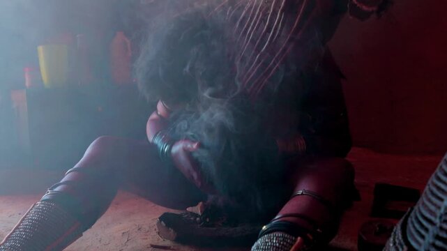 Himba woman performing a traditional smoke bath ritual in Namibia