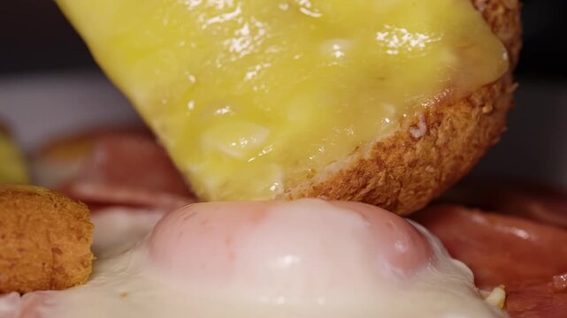 Melted Cheese Toast Breaks a Fried Egg Yolk Beside Sausages and Fried Bites in an Extreme Closeup, Indulgent Breakfast Food