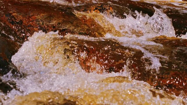 Fast flowing mountain stream rushing water close up over river rocks
