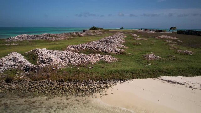 Aerial view of Los Roques archipelago featuring turquoise waters, sandy beaches, and mounds of conch shells on the shore in Los Roques, Dependencias Federales, Venezuela.