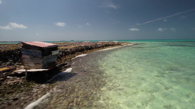 Aerial view of a small wooden shack situated on the rocky coastline of the Los Roques archipelago, surrounded by turquoise Caribbean waters in Los Roques, Dependencias Federale, Venezuela.