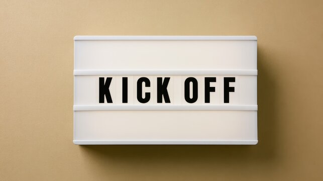 A glowing lightbox displaying the words Kick Off mounted on a plain neutral background. Great concept for corporate project starts and business presentations.