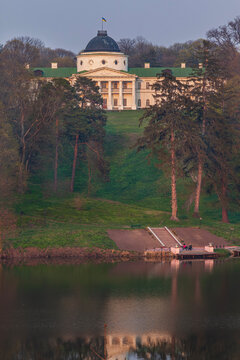 Beautiful vertical view of an old antique palace mansion on a green hill reflecting in the lake