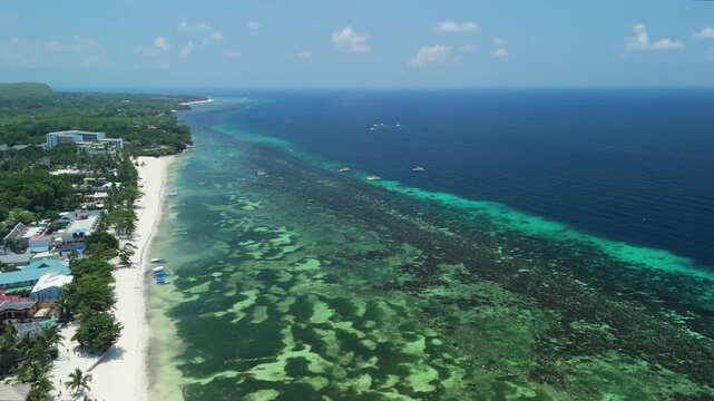 Aerial view of Alona Beach featuring white sand, turquoise waters, and coral reefs along the coast of Panglao, Bohol, Philippines.