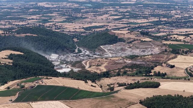 Aerial of quarry industrial site green forests golden fields and vast rural plain under clear sky