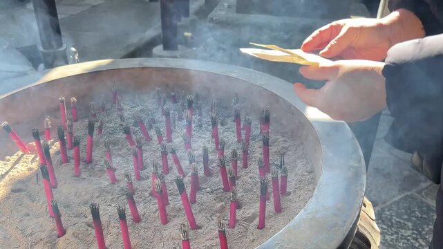 神社で濡れたお札を線香の熱に近づけて乾かす様子