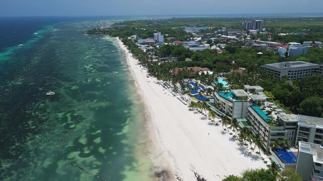 Aerial view of Alona Beach with white sand, turquoise waters, and resort hotels along the coastline in Panglao, Bohol, Philippines.