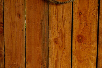 Warm, rustic wooden plank background with visible grain, knots, and a rope detail at the top. © vegefox.com