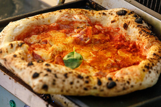 Close-up of a freshly baked Neapolitan pizza with tomato sauce, mozzarella, paprika, and a basil lea