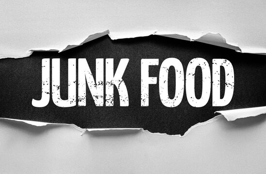 Torn paper reveals the bold grunge words JUNK FOOD underneath, symbolizing unhealthy eating, processed snacks, and dietary concerns breaking through a surface with distressed typography