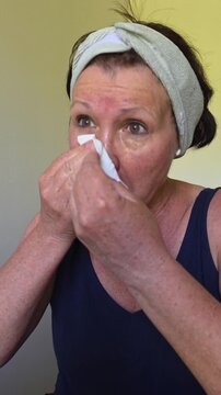 A woman wipes her face with a tissue. vertical video.