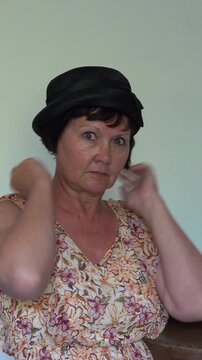 A woman puts on a retro black hat at home. vertical video.