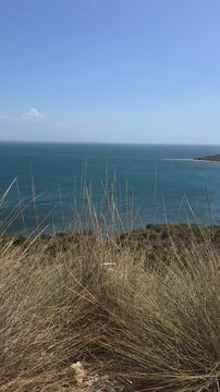 Panoramic view from El Morro, Montecristi, Dominican Republic &mdash; a dramatic coastal cliff overlooking the deep blue Caribbean Sea and a natural bay. Dry coastal vegetation and wild grass frame the scen
