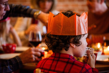Naklejka premium Child with curly hair wearing a paper crown at a festive gathering.