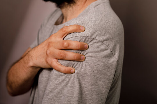 Close up of a man experiencing shoulder pain grasping his arm