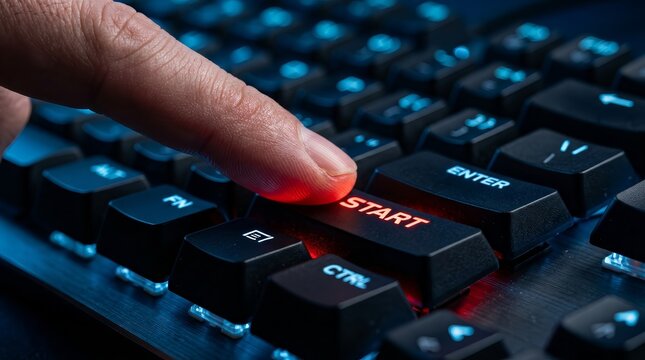 Technology concept showing a hand pressing a glowing red start key on a dark keyboard.