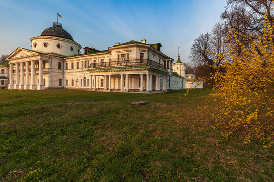 Beautiful scenic view of an old antique classic palace mansion with yellow forsythia flowers in spring park