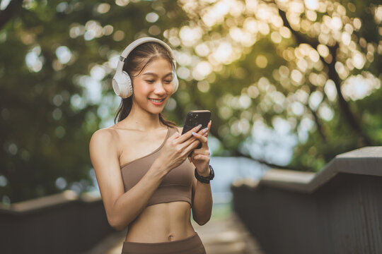 Happy sporty woman using smartphone and wearing headphones outdoors, fitness, music and active lifestyle