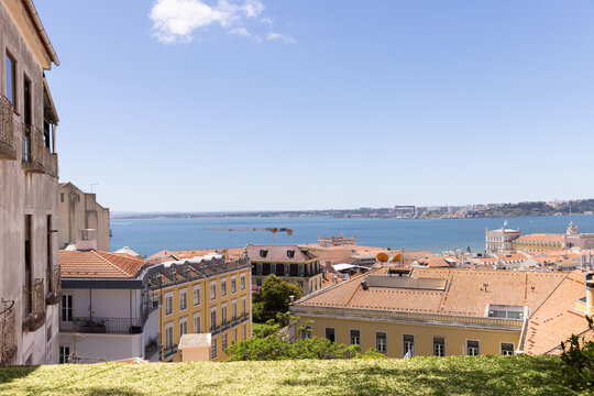 wide landscape shot of Lisbon, Portugal with orange tiled roofs looking towards Tagus River on a sunny clear day