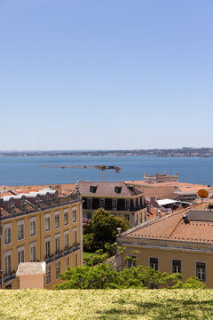 wide landscape shot of Lisbon, Portugal with orange tiled roofs looking towards Tagus River on a sunny clear day