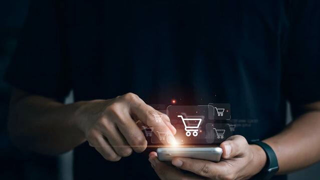 Man using smartphone for online shopping with digital shopping cart icon holographic interface