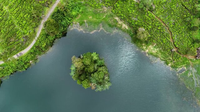 Aerial view of Patenggang Lake with its small forested island surrounded by calm waters and lush greenery in Rancabali, West Java, Indonesia.