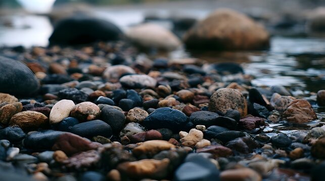 Close up of multicolored river stones partially submerged in calm water with shallow depth of field