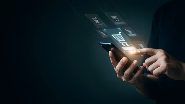 Close up of hand using smartphone with virtual shopping cart icons for e-commerce concept