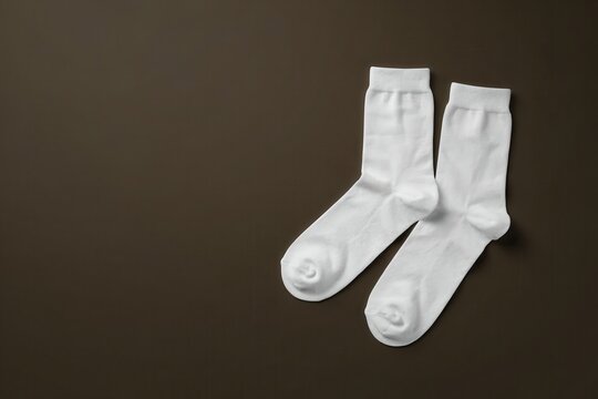 Pair of white cotton socks on a dark brown background