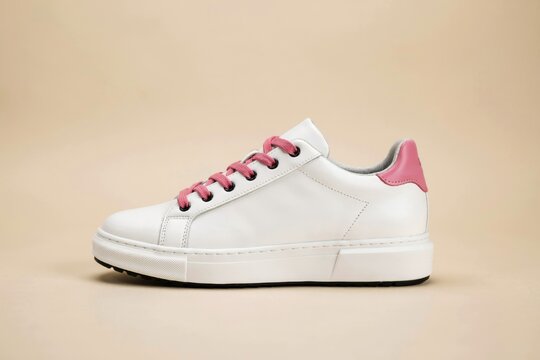 White leather sneaker with pink laces and heel detail on beige background