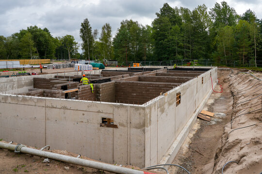 Concrete Basement Construction with Masonry Walls and Workers at Large Residential Building Site