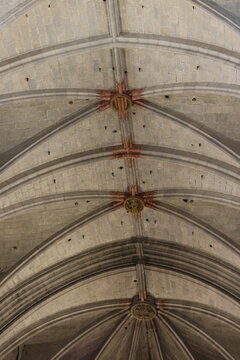 Historic Gothic vaulted ceiling inside a medieval cathedral featuring stone rib vaults, decorative bosses and heraldic symbols. Architectural detail showcasing craftsmanship, symmetry and European rel