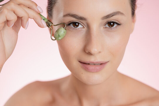 Woman using a jade roller for facial massage and skincare routine