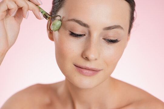 Woman using a jade roller for facial massage and skincare routine