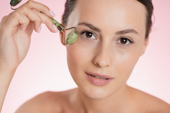 Woman using a jade roller for facial massage and skincare routine