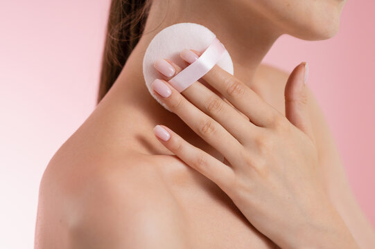 Woman applying powder puff to her neck and shoulder for a flawless complexion
