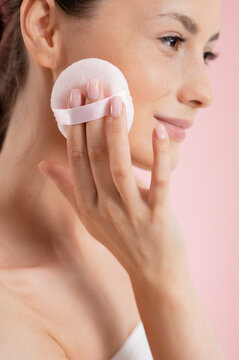 Woman applying powder puff to her cheek for a flawless makeup look