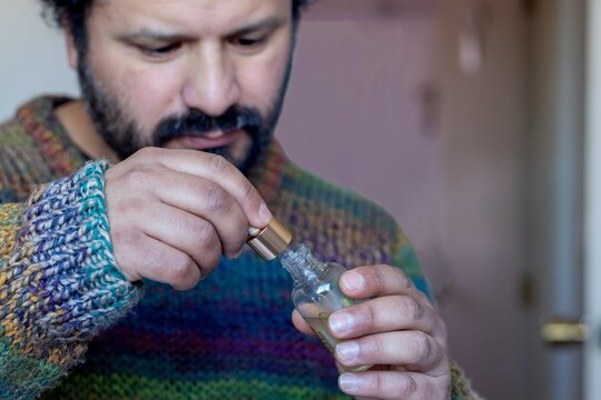 Bearded Man Using Dropper Bottle Indoors