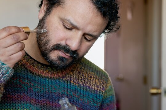 Man smelling liquid from a glass dropper