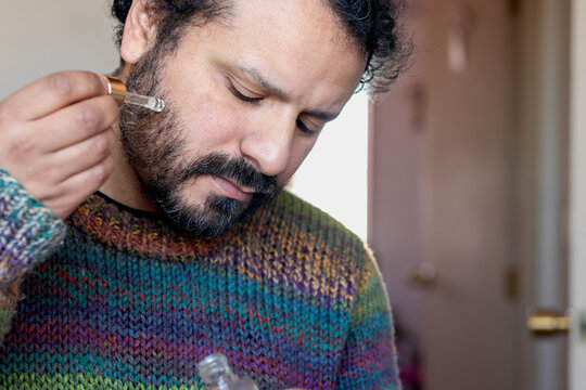 Bearded man applying facial serum at home