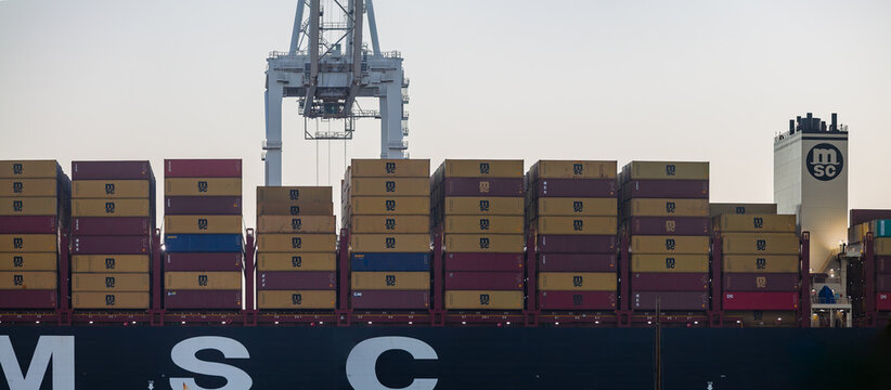 Maritime freight ship loaded with containers and illuminated by onboard lighting during busy port operations in Oakland, California