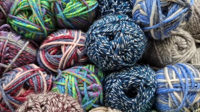 Colorful melange woolen yarn balls stacked together close up. Knitting and crochet hobby materials, textile craft background, handmade apparel supplies.