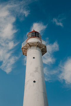 View of the white Saxby Lighthouse against a bright blue sky with wispy clouds in Saxby, Laane maakond, Estonia.