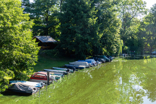 Idyllische Flusslandschaft mit ruhigen Parkteichen und kleinen Booten am Steg in Brandenburg, Deutschland