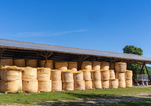 &Uuml;berdachte Lagerhalle auf einem Bauernhof mit ordentlich gestapelten Rudnballen aus Stroh, Photovoltaikanlage auf dem Dach der Halle, Uckermark, Brandenbugr, Deutschland