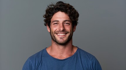 Obraz premium Studio headshot of a cheerful young man wearing a blue tee with a warm, inviting smile