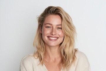 Fototapeta premium Studio portrait of a joyful woman with fair hair in casual wear against a plain backdrop