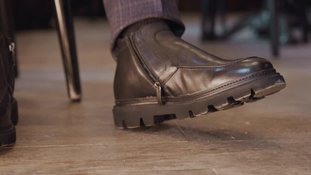 Close up of man hand adjusting zipper on his black leather boot showcasing detailed craftsmanship and texture. scene features soft lighting that highlights material quality while maintaining