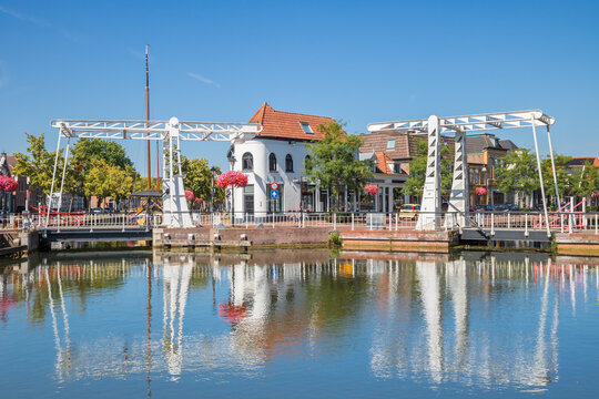 Two white bridges reflect on calm canal water under a bright sky in Meppel, Netherlands